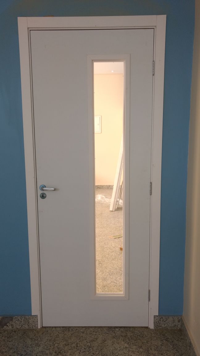 Uma porta branca com uma janela em uma sala com uma parede azul.