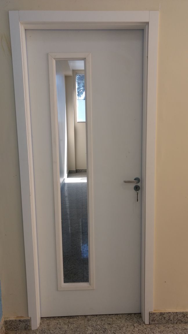 Uma porta branca com uma janela de vidro em um corredor.