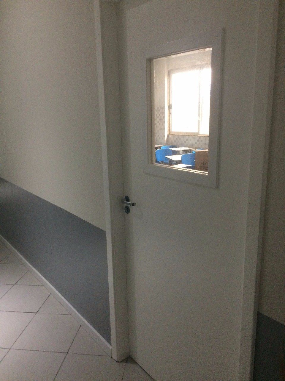Uma porta branca com uma janela em um corredor.