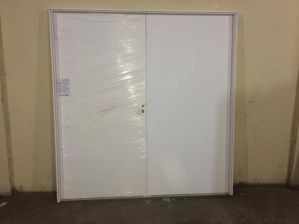 Uma porta branca está envolta em plástico e apoiada na parede.