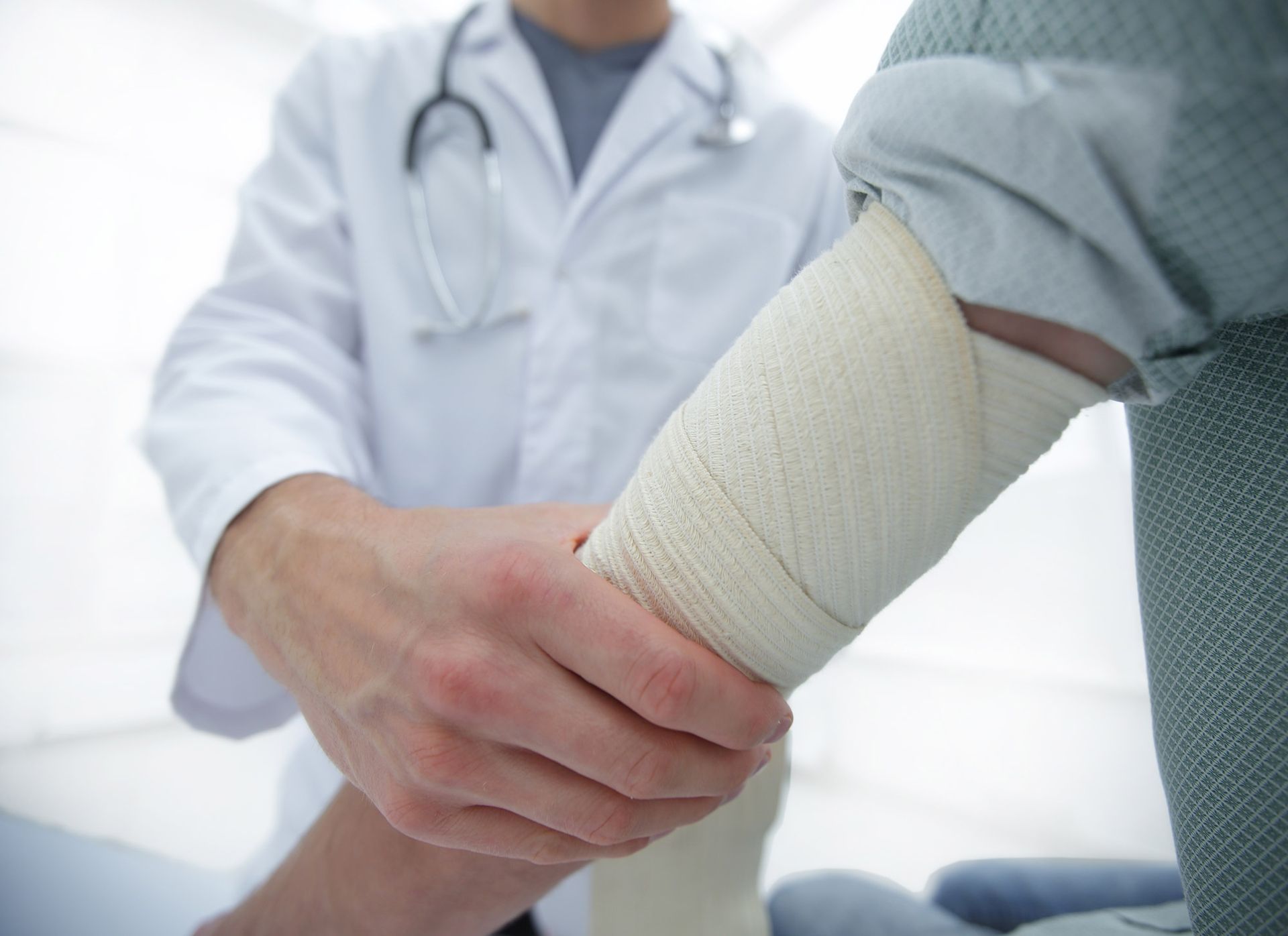 Doctor wrapping a patient's bandaged arm.