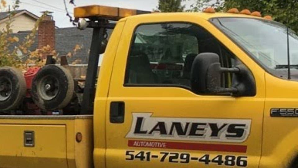A yellow laneys tow truck is parked in front of a house.