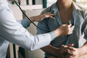A doctor is listening to a patient 's heart with a stethoscope.