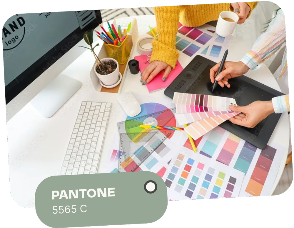 A designer working on a project at a desk with color swatches and a tablet. Features Pantone 5565 C.