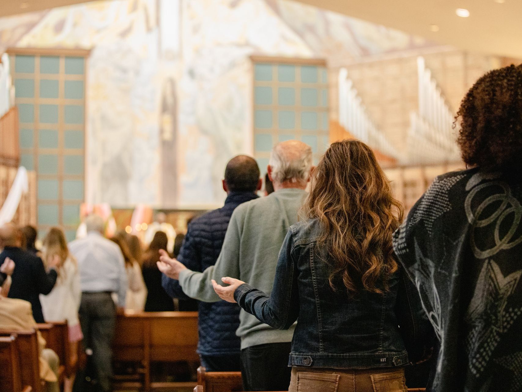 People standing in a church or chapel during a service, facing the altar.