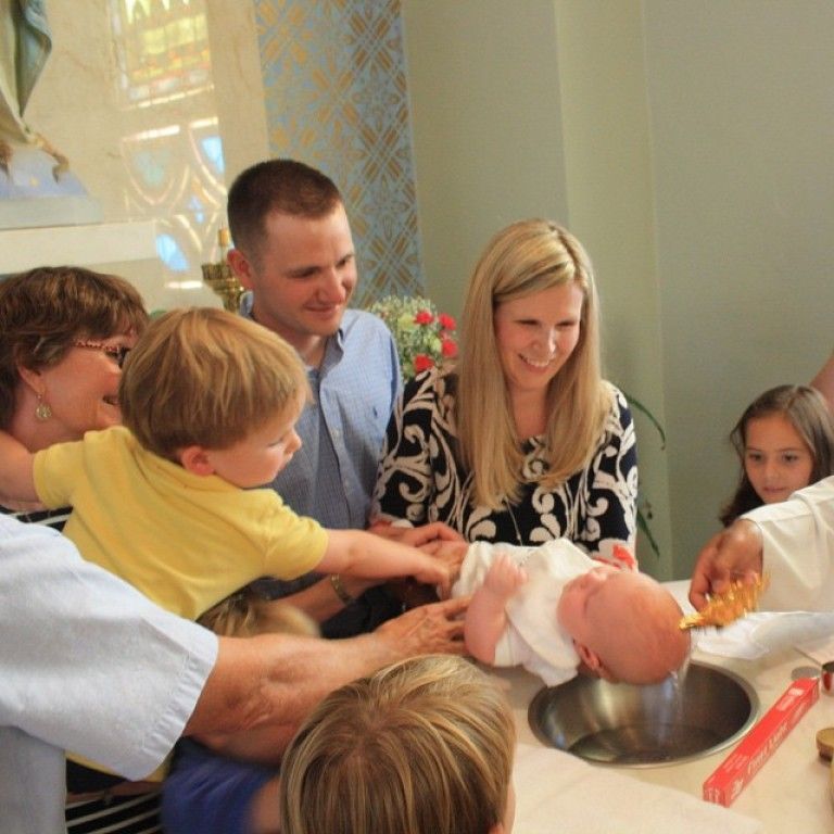 People gathered around a baby being baptized in a church basin