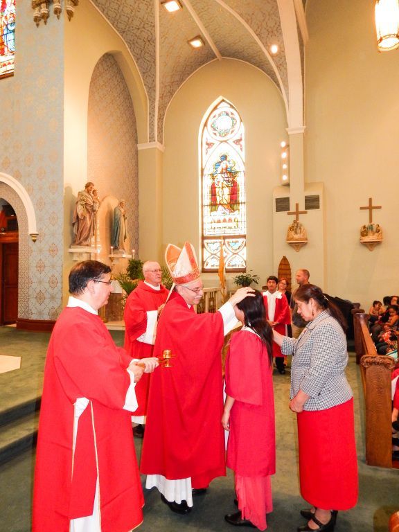 Clergy in red robes greeting a woman inside a church during a religious ceremony