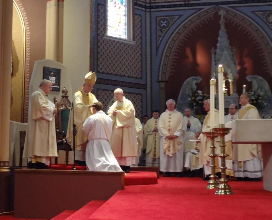 Clergy in white robes gathered at an altar in a cathedral during a religious ceremony