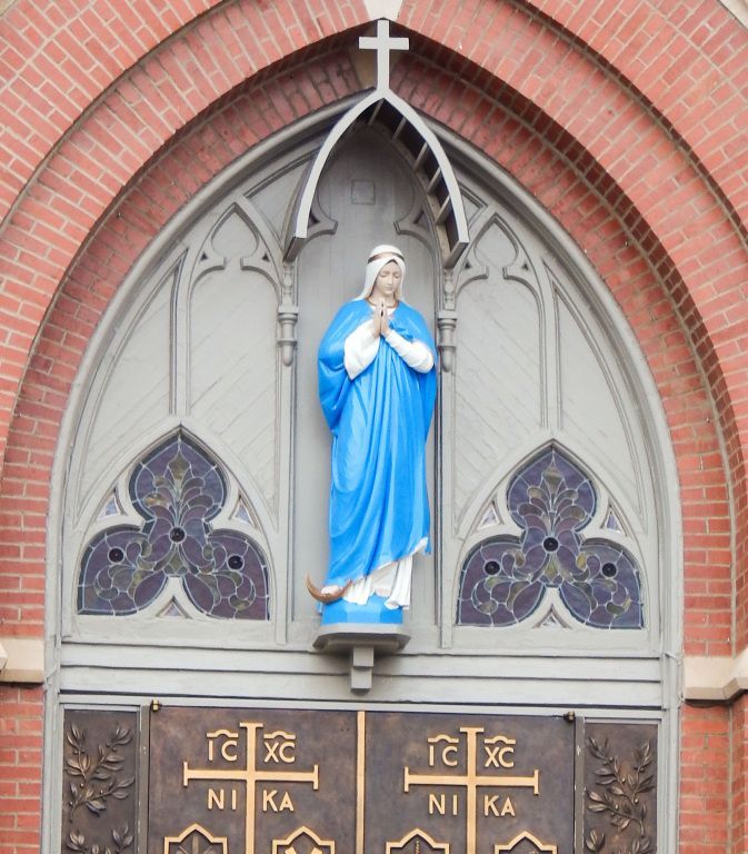 Blue-and-white statue of the Virgin Mary in a church alcove above decorative doors