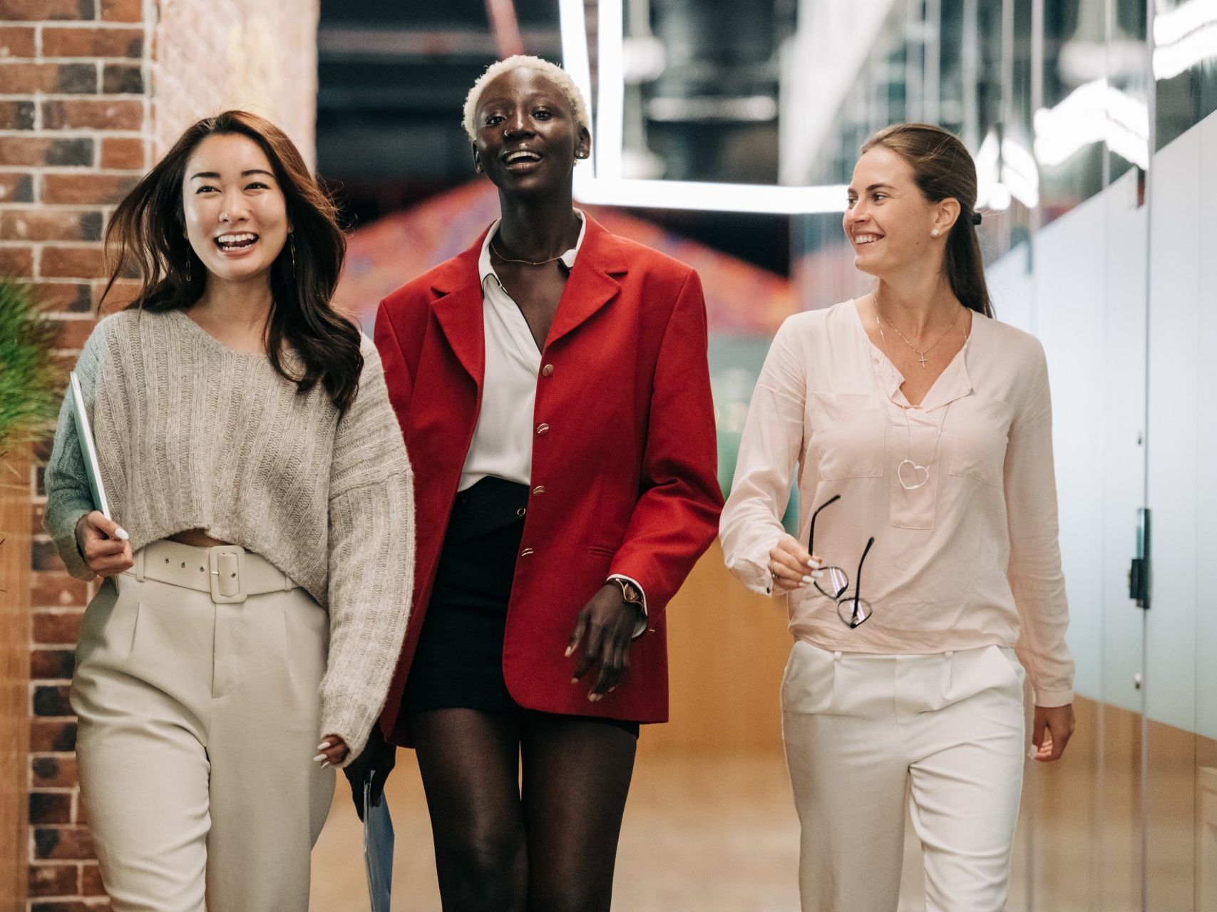 3 women of different cultural backgrounds at work smiling together.