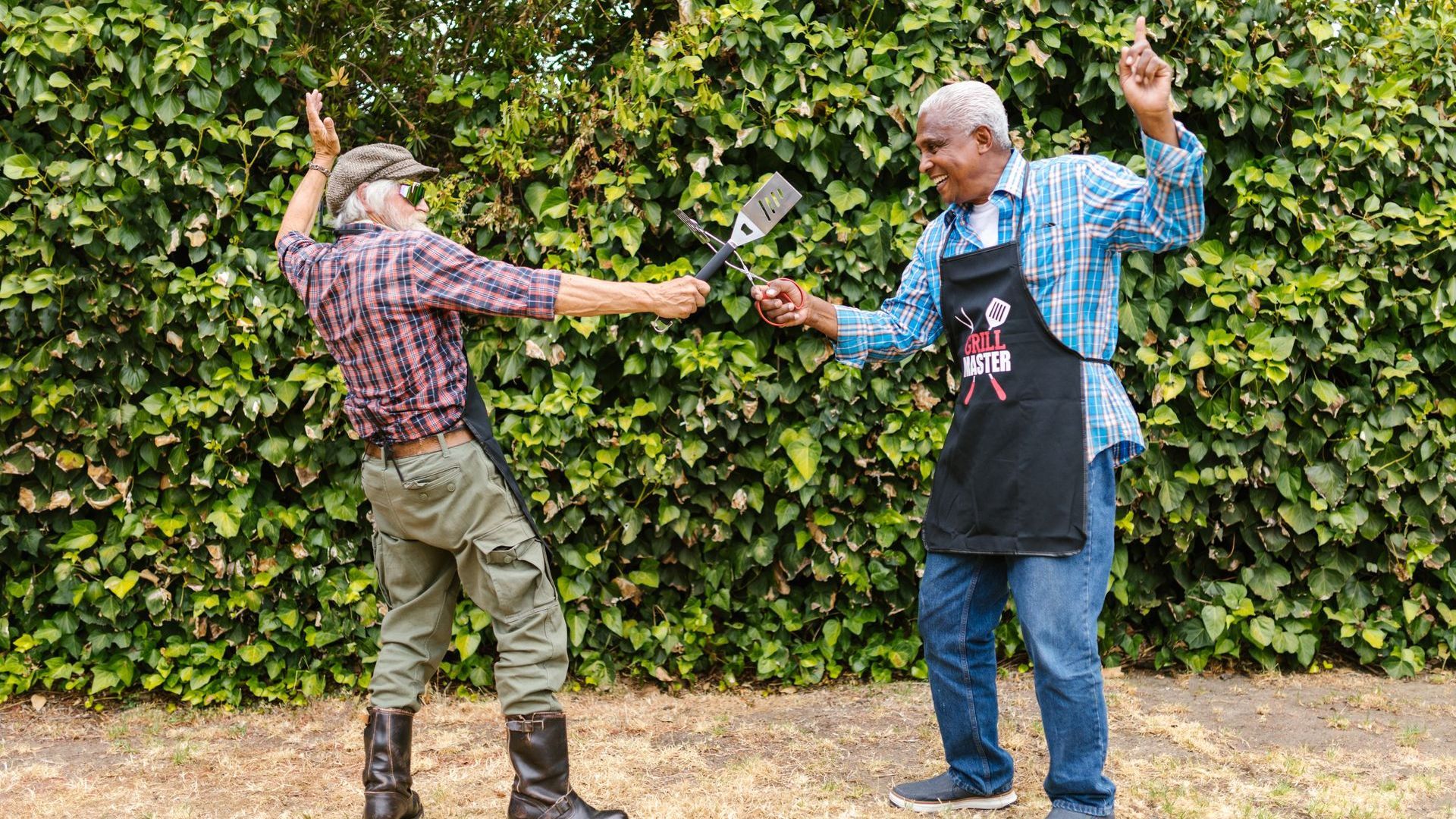 two men BBQ and tapping spatulas in a playful manner.