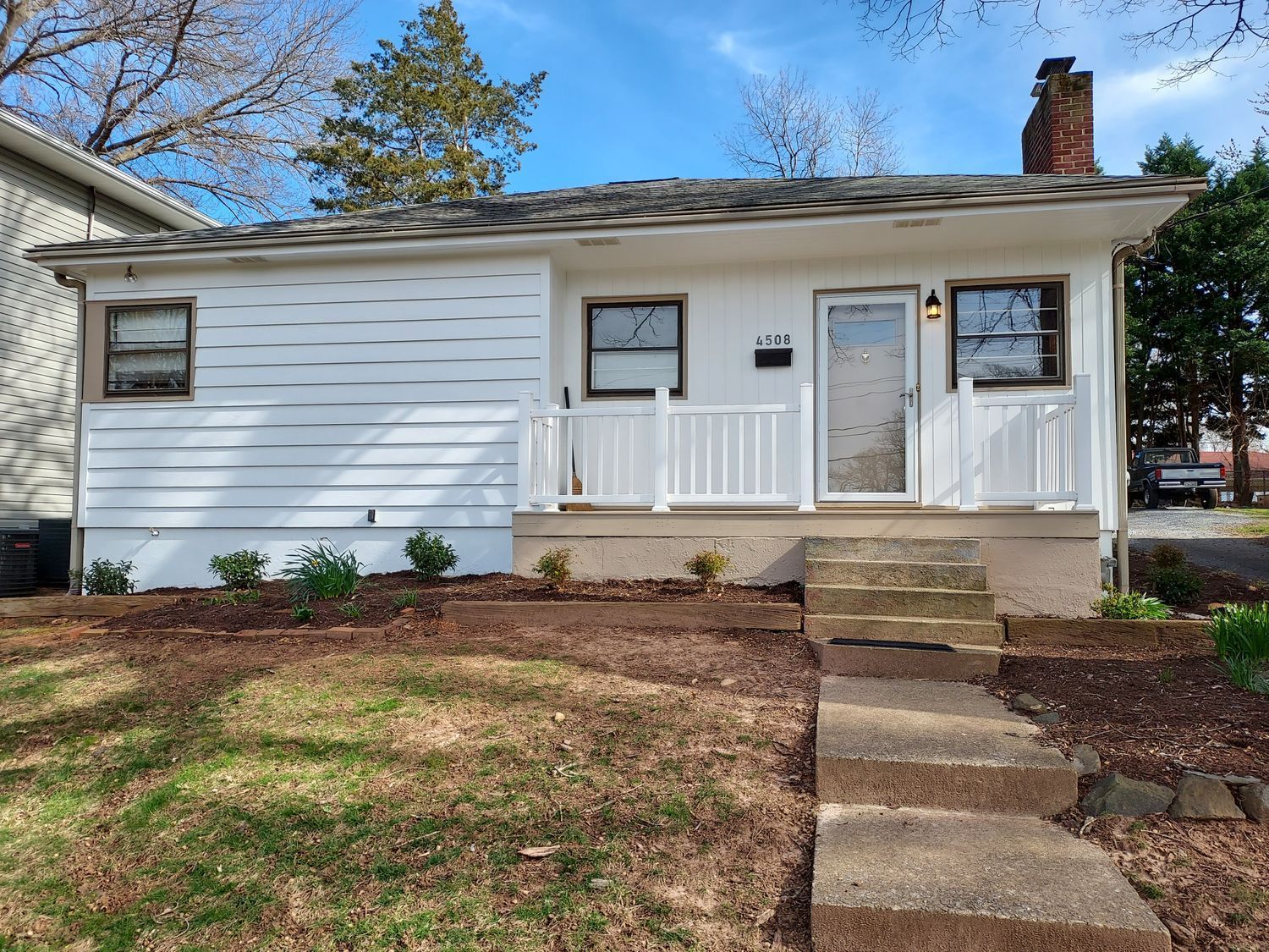 A small white house with stairs leading up to the front door.