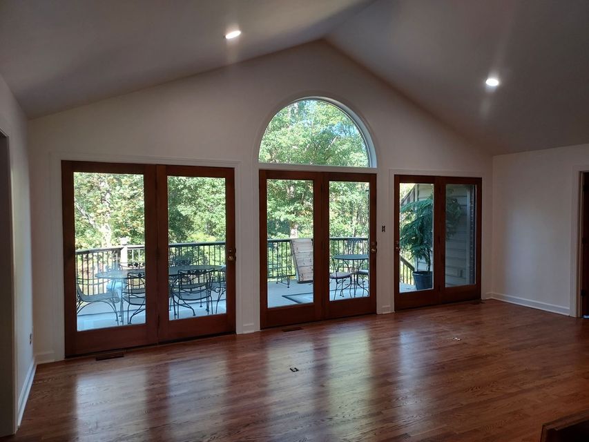 An empty living room with hardwood floors and lots of windows