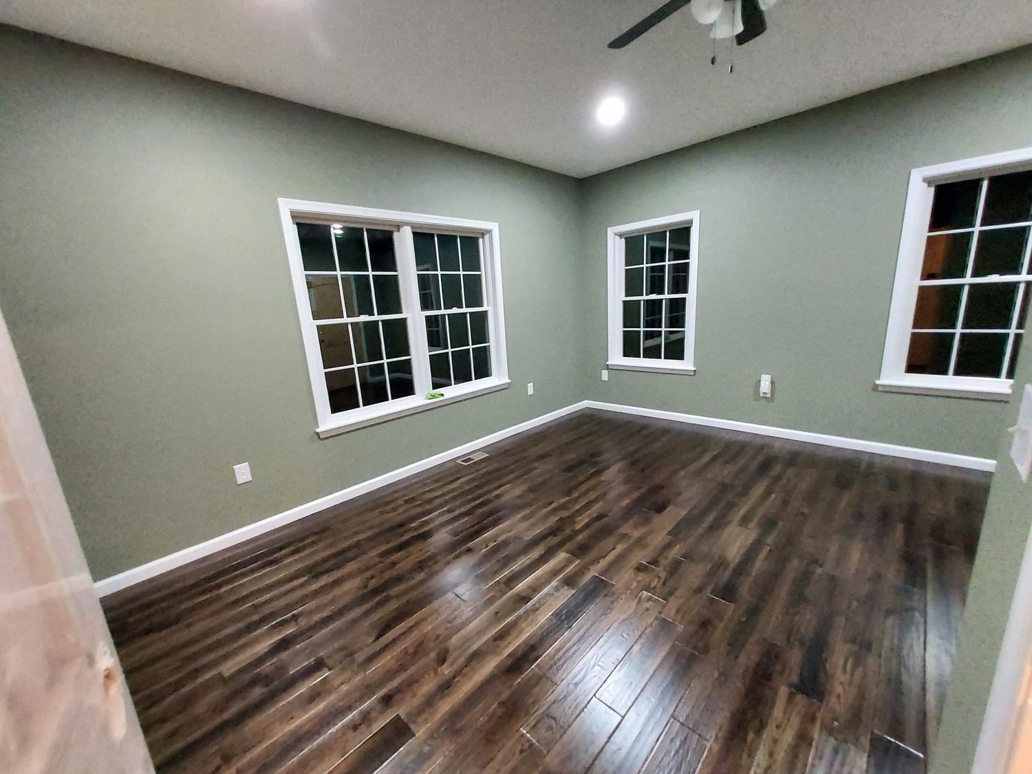 An empty room with hardwood floors and a ceiling fan.