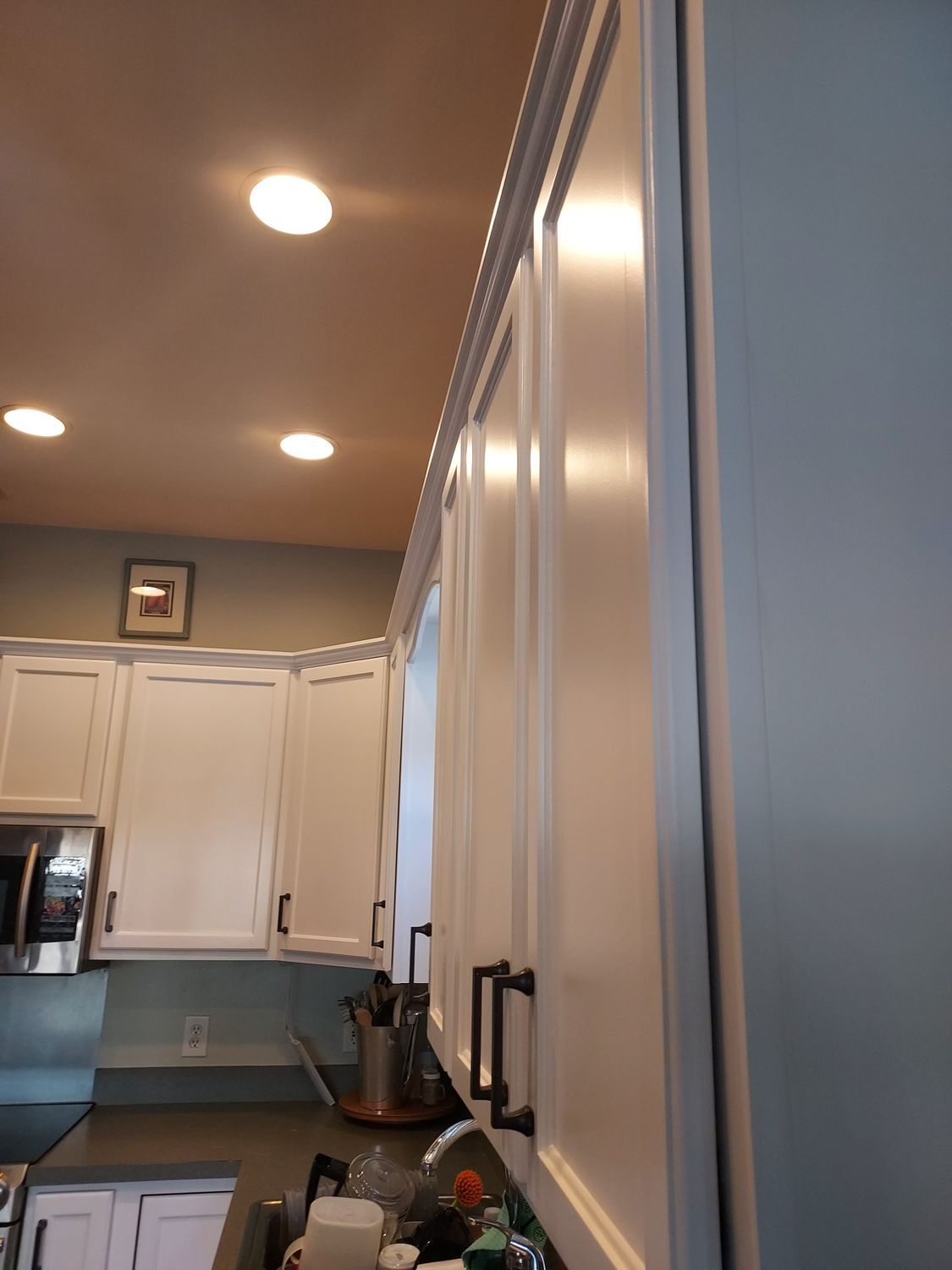 A kitchen with white cabinets , a sink , and a microwave.