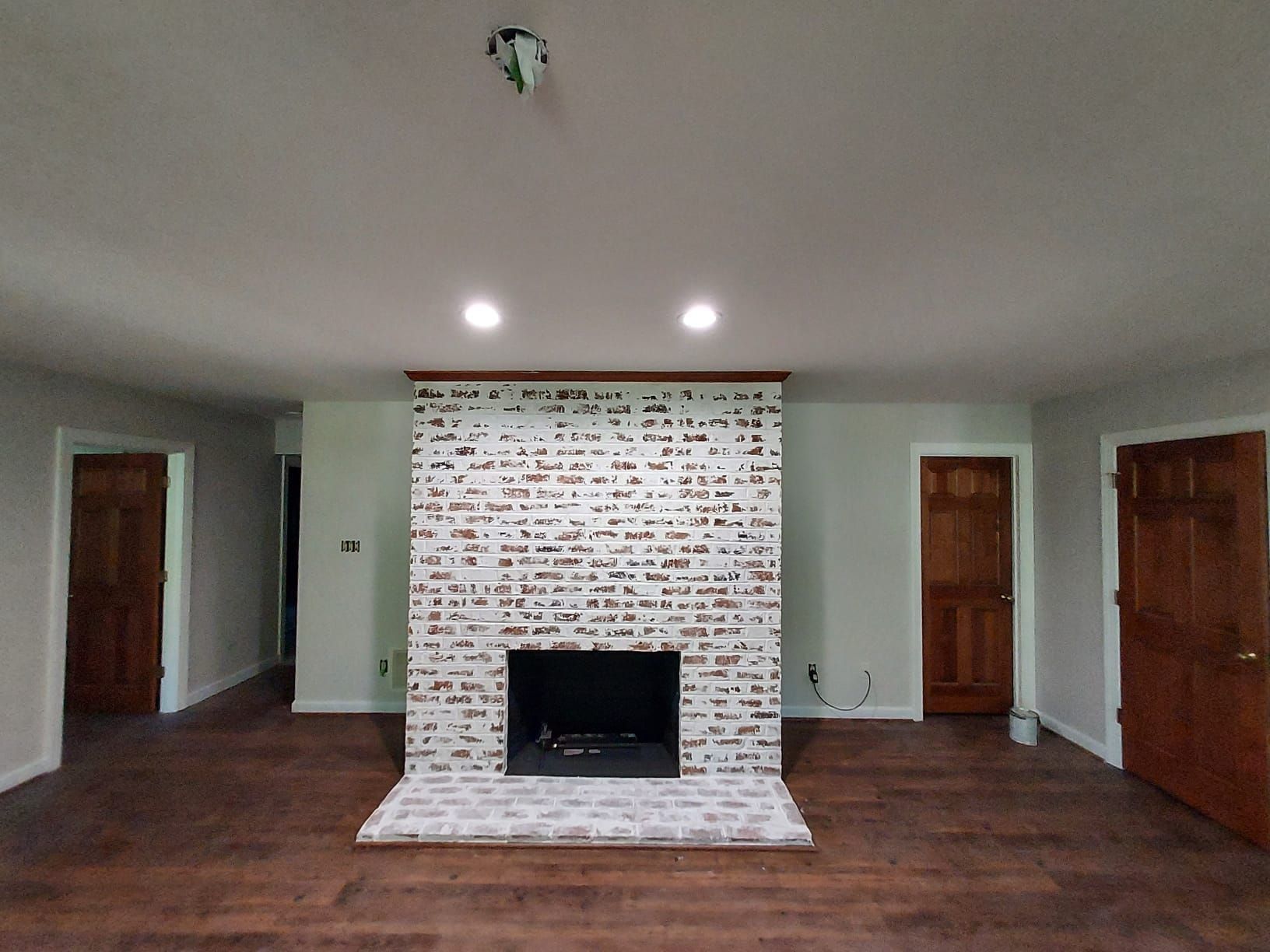A living room with a brick fireplace and wood floors