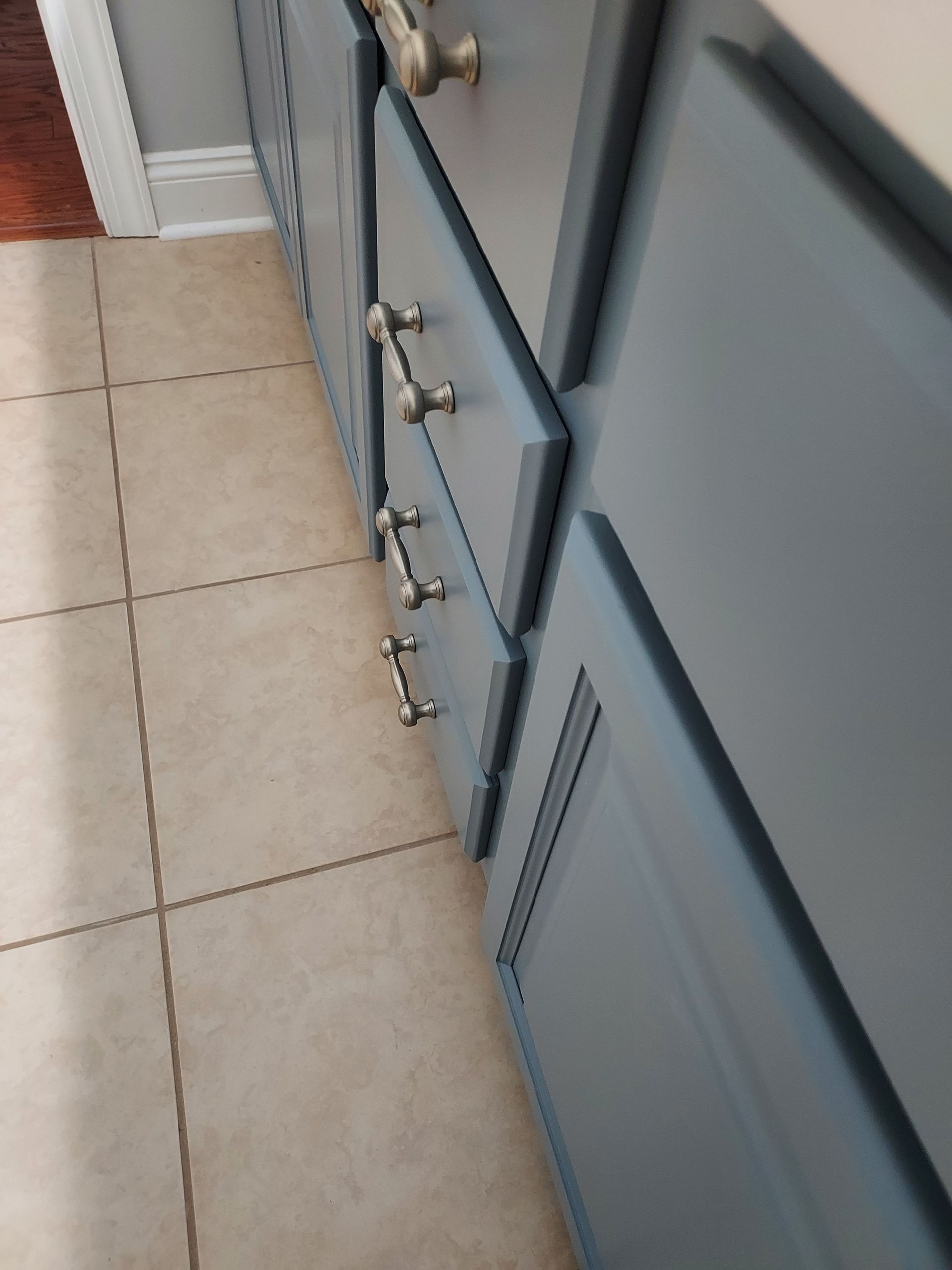 A kitchen with white cabinets , a sink , and a microwave.