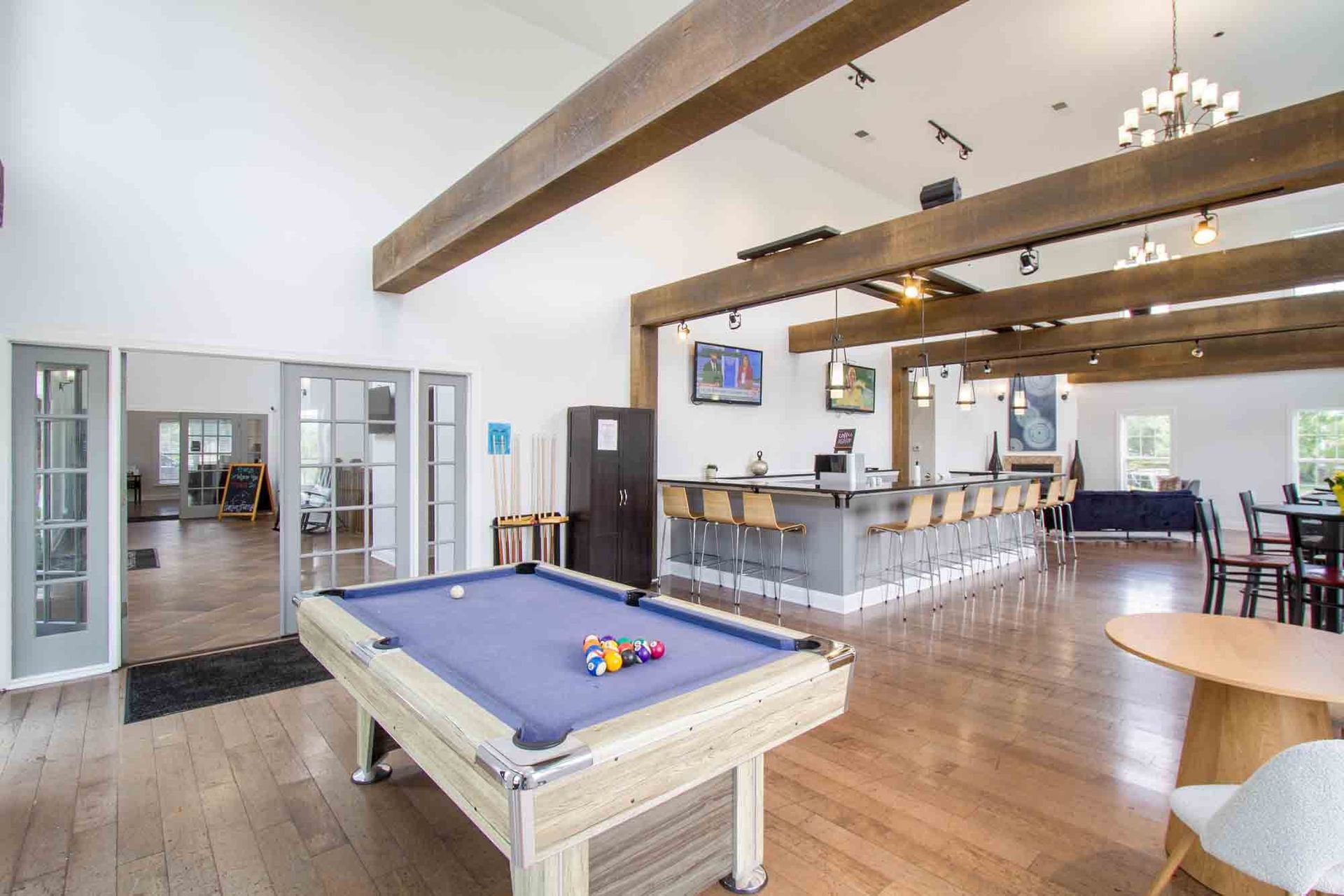 Interior shot of a rec room with pool table, bar, seating, wooden beams, and access to other rooms at Hamburg Farms, offers apartments in Lexington, KY.
