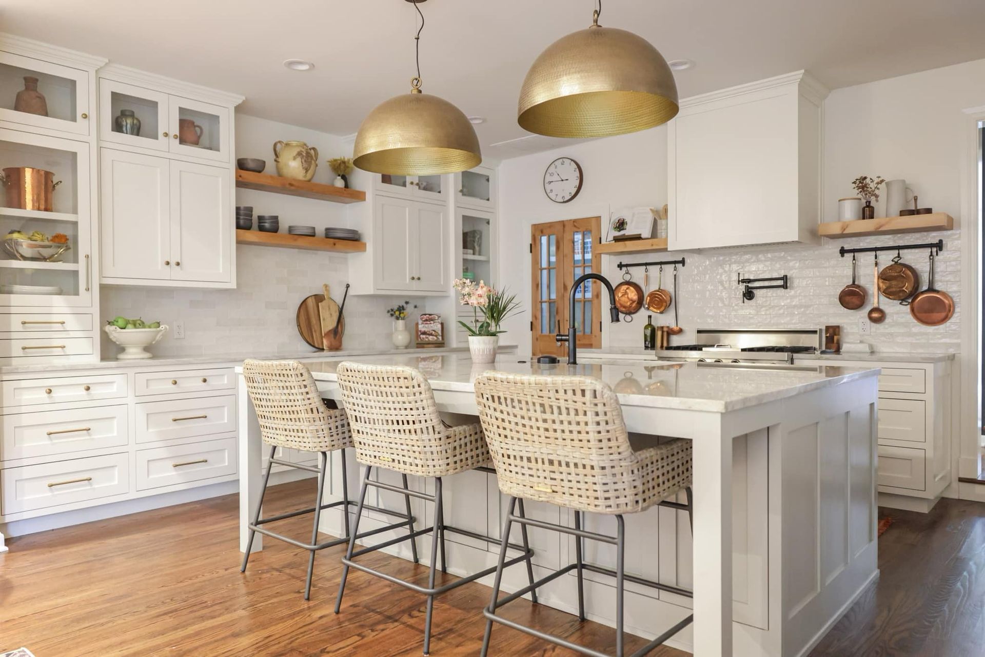 A kitchen with white cabinets , wooden floors , and a large island.