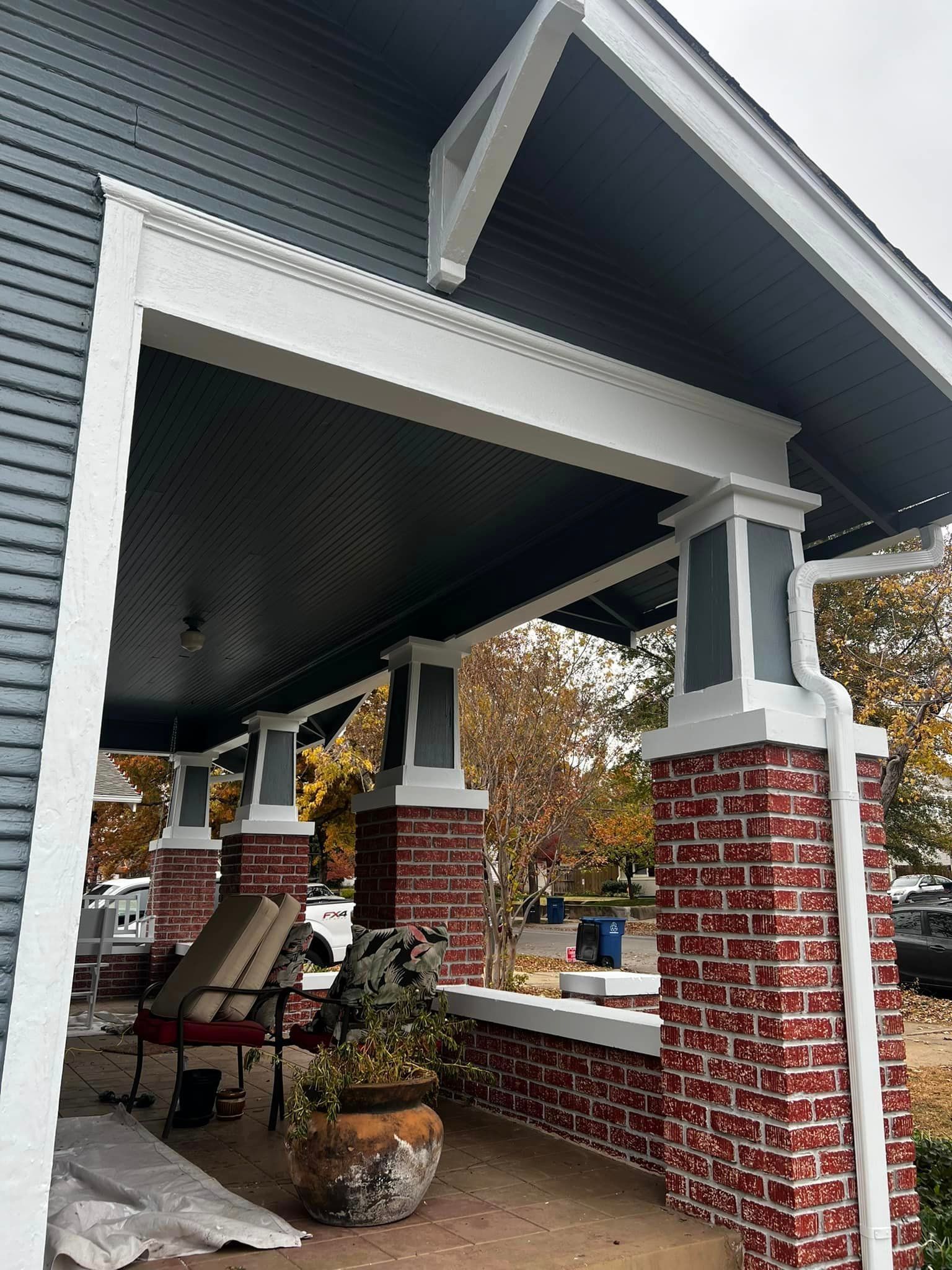 The porch of a house with a brick wall and a black roof.