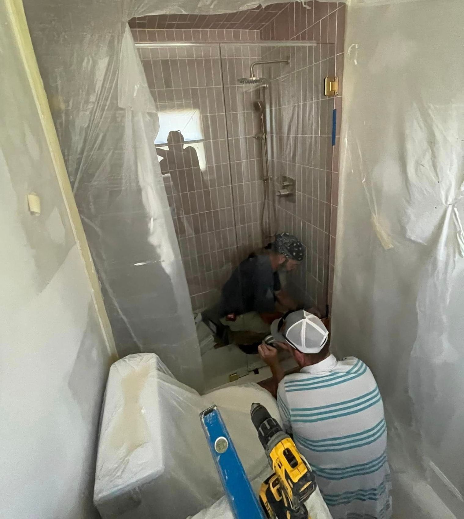 A man is working in a bathroom with a drill.