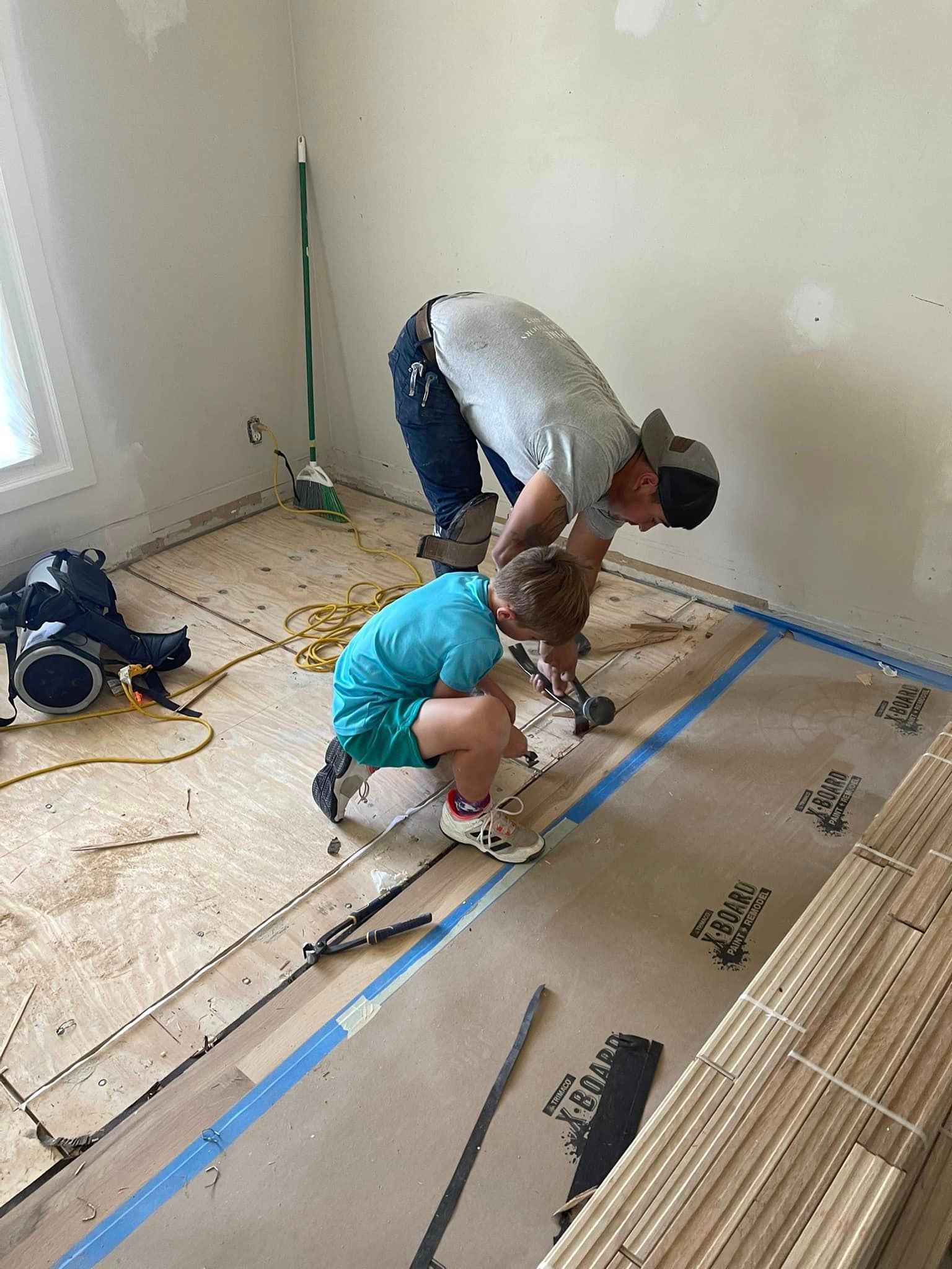 A man and a child are working on a floor in a room.