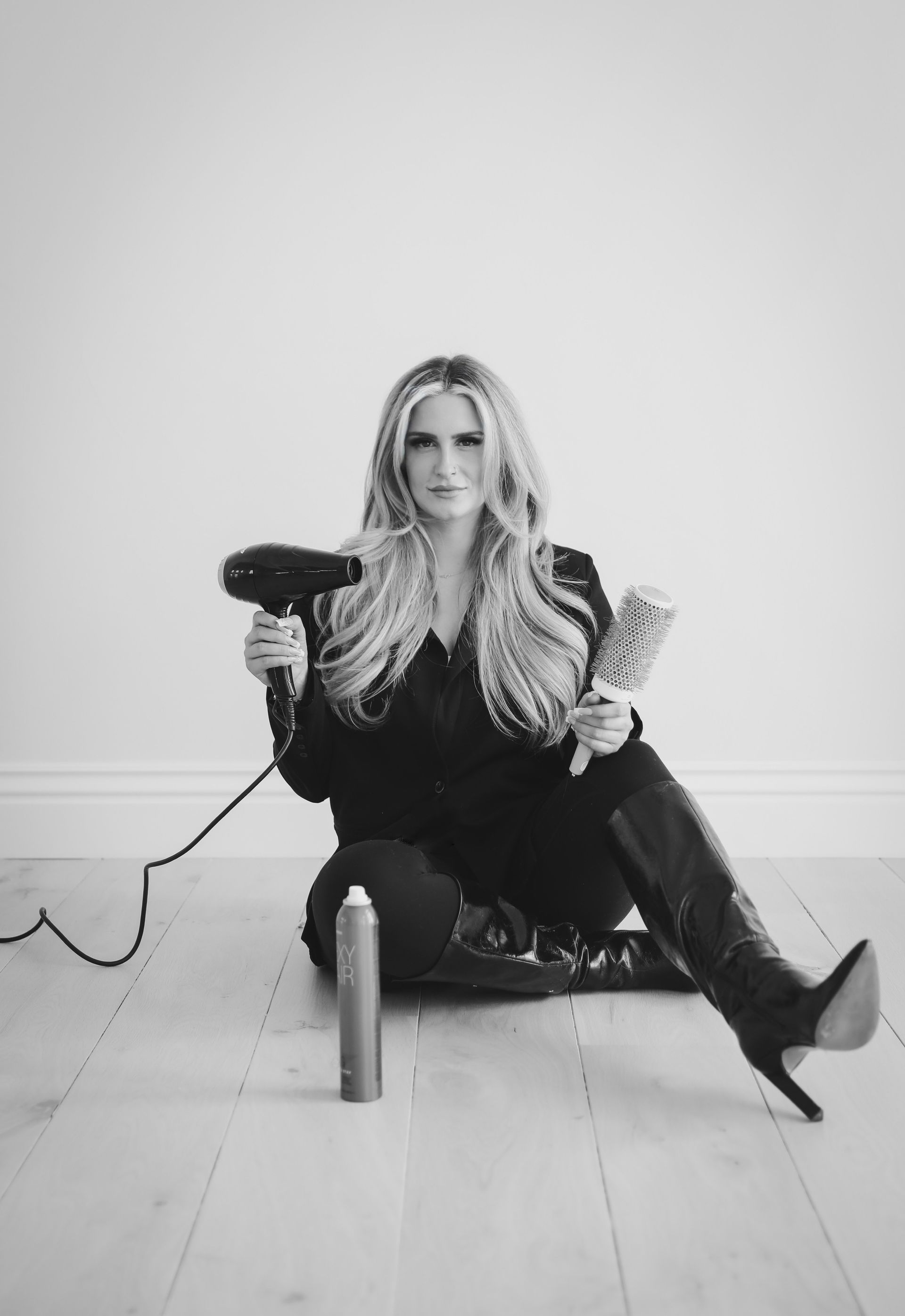 A woman is sitting on the floor holding a hair dryer.