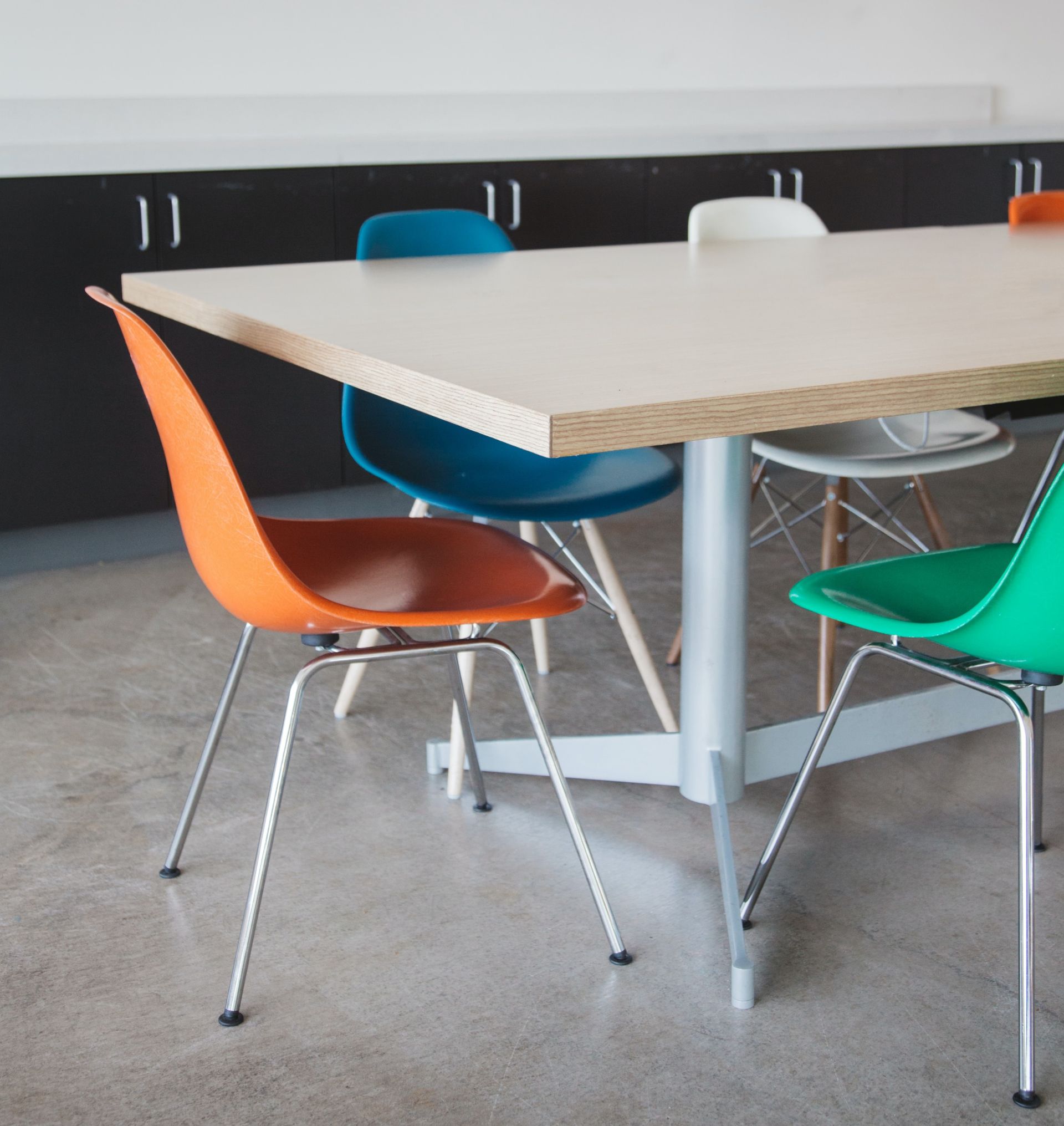 a table with four chairs on it including orange blue and green