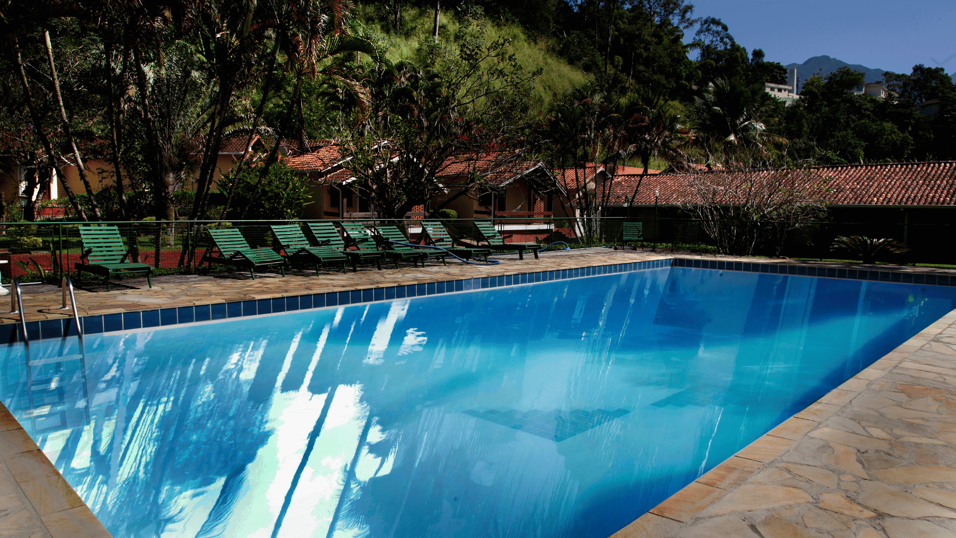 Uma grande piscina cercada por cadeiras e árvores