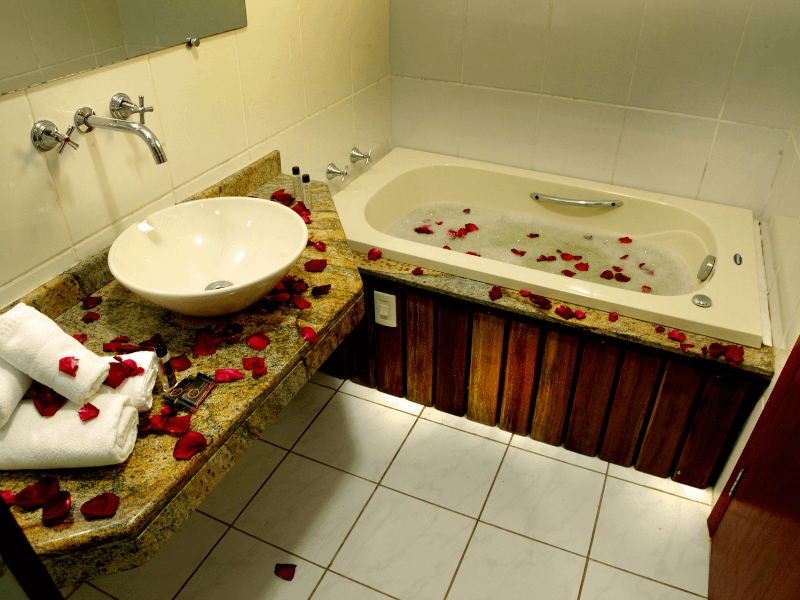 Um banheiro com pia e banheira cheia de pétalas de rosa