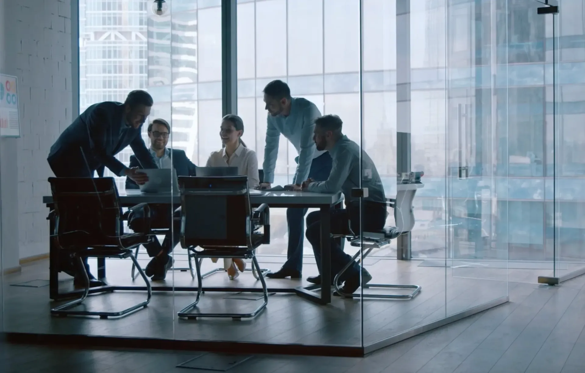 A group of people are having a meeting in a glass conference room.