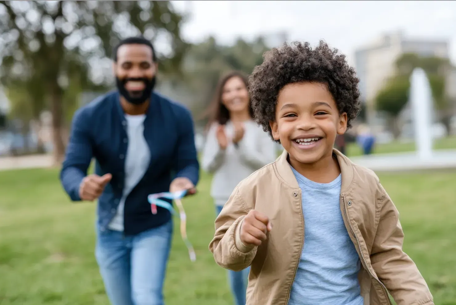 A man , woman and child are happy in a park.