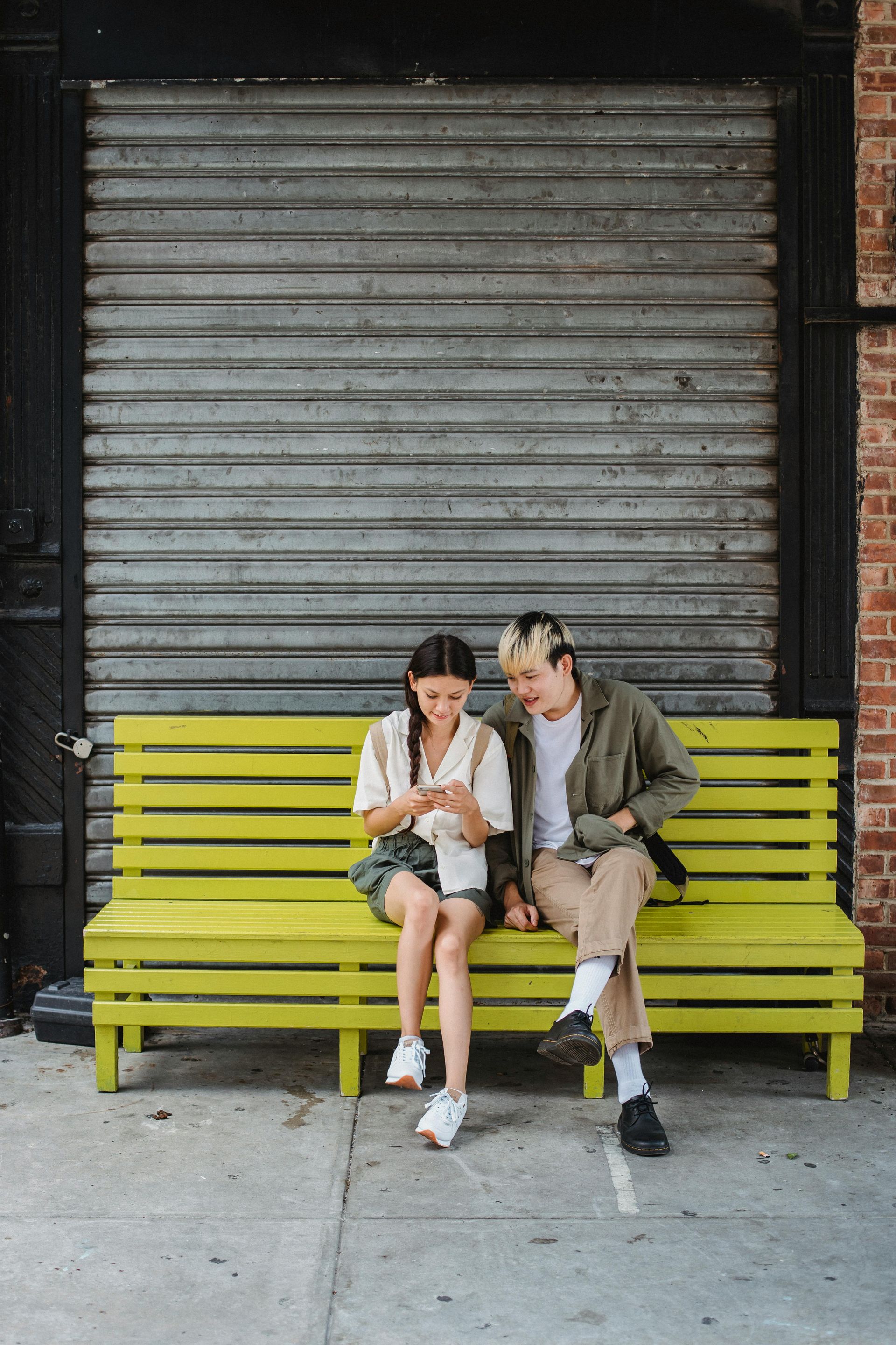 Two people sitting on a bench looking at a mobile-optimised website