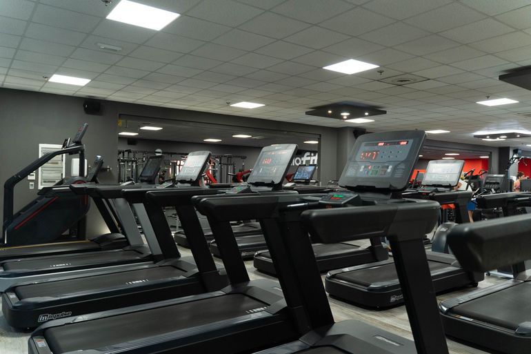 Interno della palestra con vari attrezzi ginnici e una parete rossa con il logo 