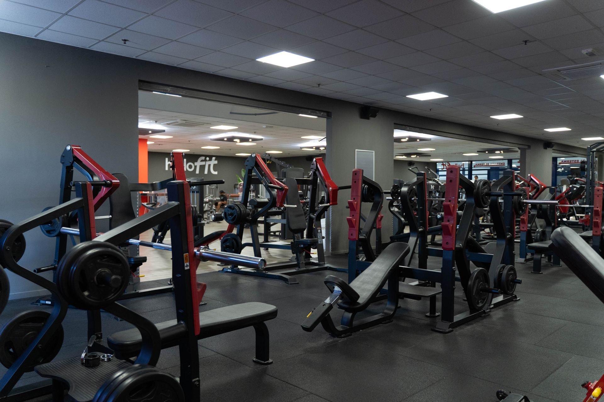 Bilanciere con disco nero, appoggiato su un tappetino blu in una palestra.