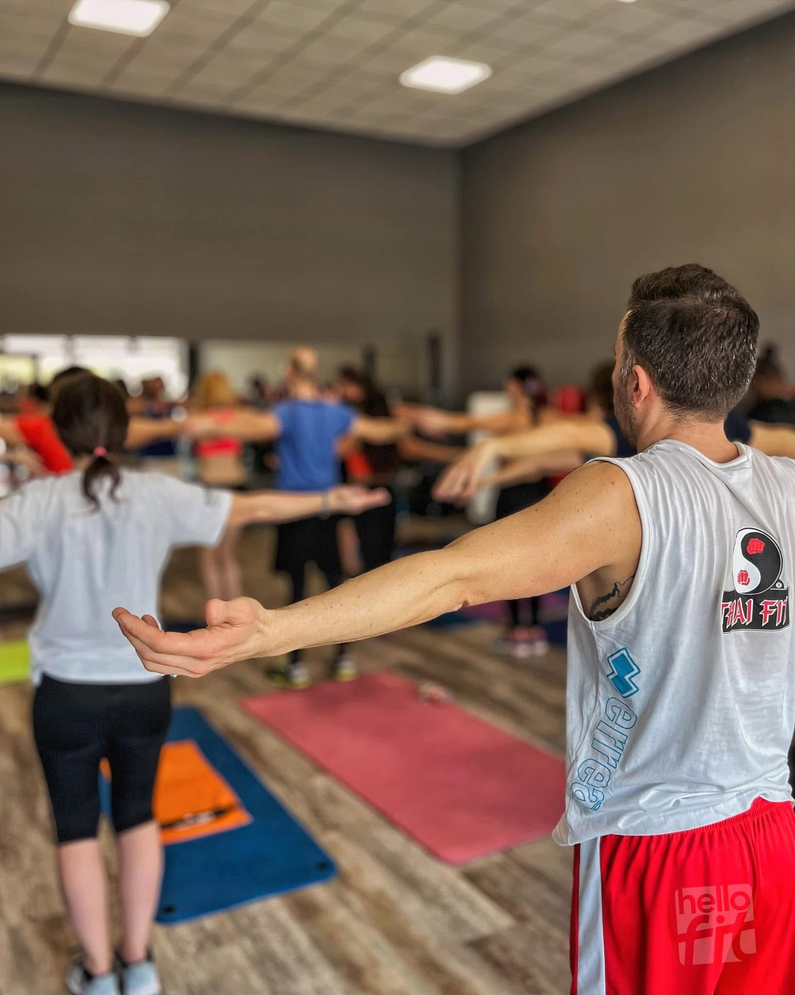 Donna in tenuta da palestra che fa flessioni su un tappetino. Capelli biondi raccolti in una coda di cavallo, sorridente in palestra.