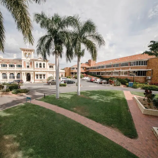 Courtyard with palm trees between a white historic-style building and a red-brick modern building