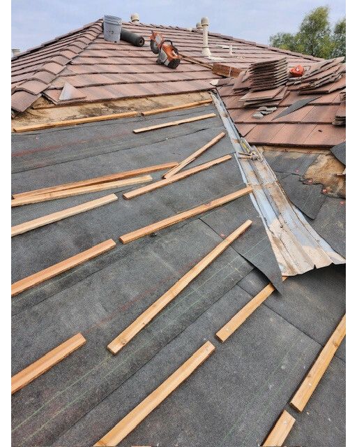 The roof of a house is being repaired with wooden beams