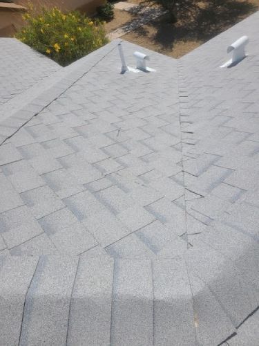 A close up of a roof with shingles and a skylight.
