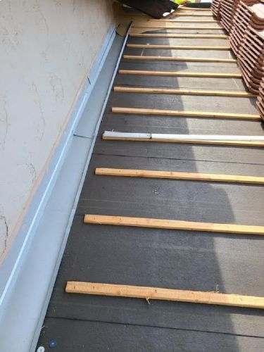 A row of wooden slats are lined up on a roof