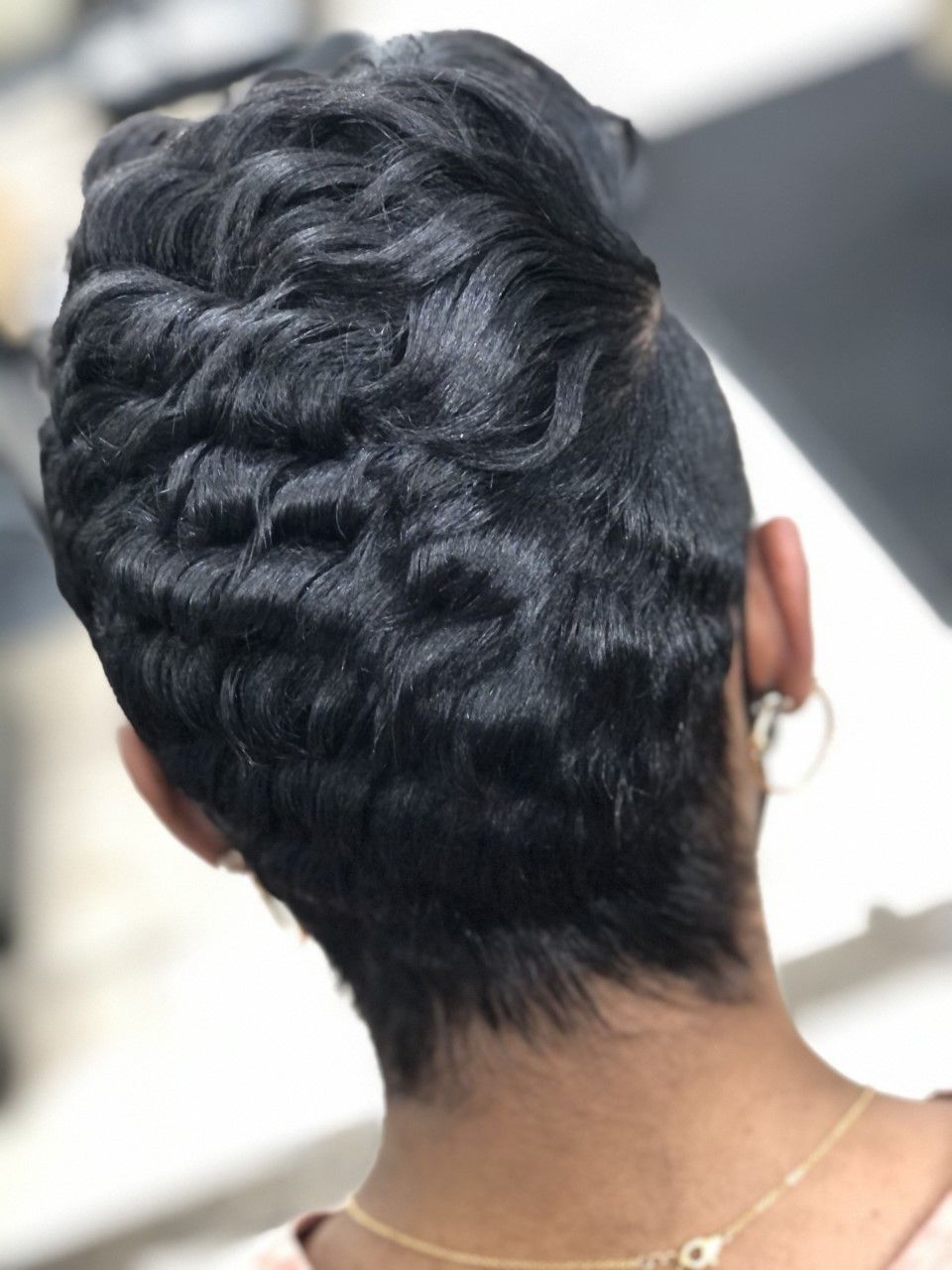 Close-up of the back of a person's head with a short, textured, dark hairstyle.