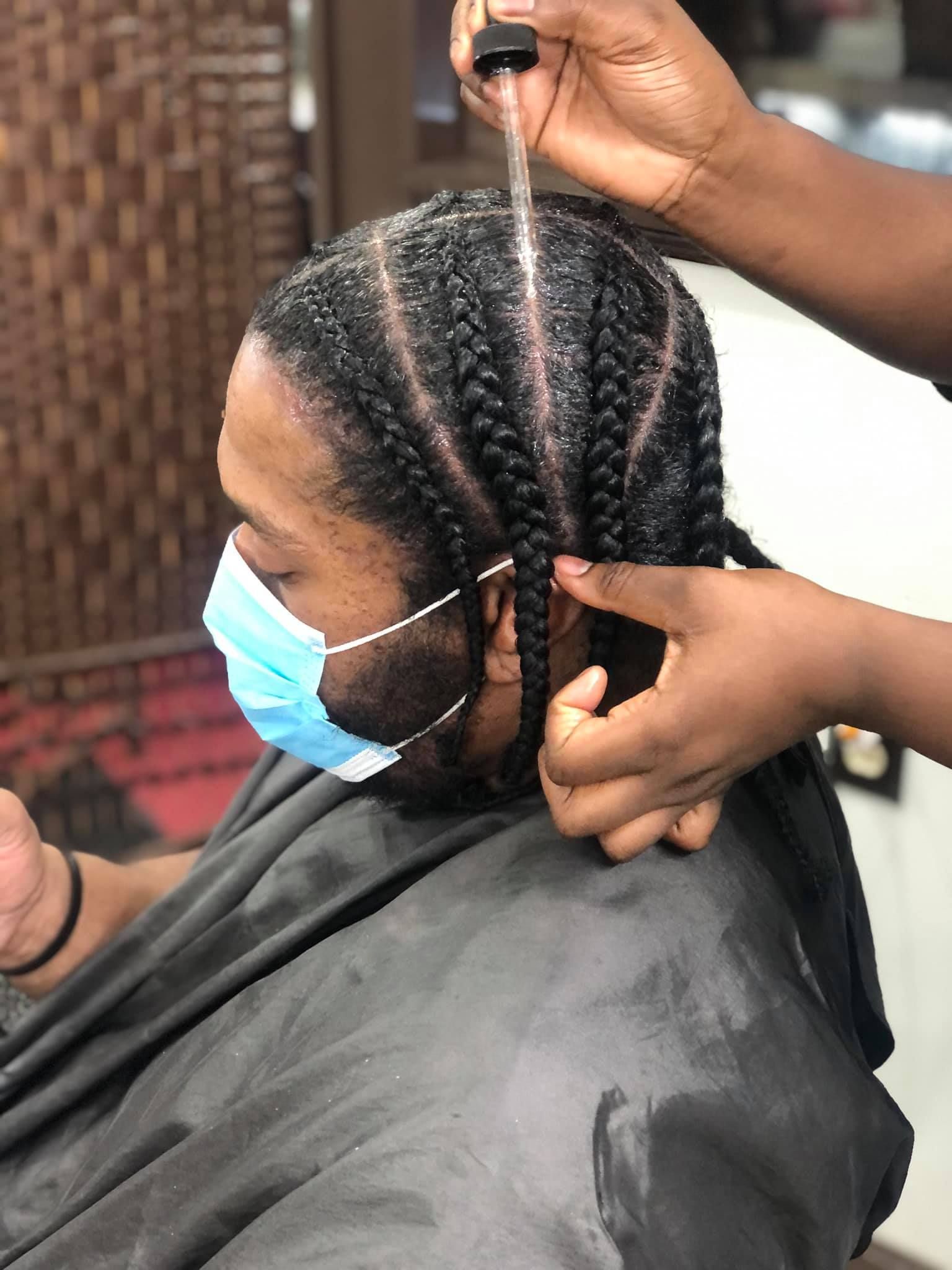 Person getting hair braided, wearing a face mask. 