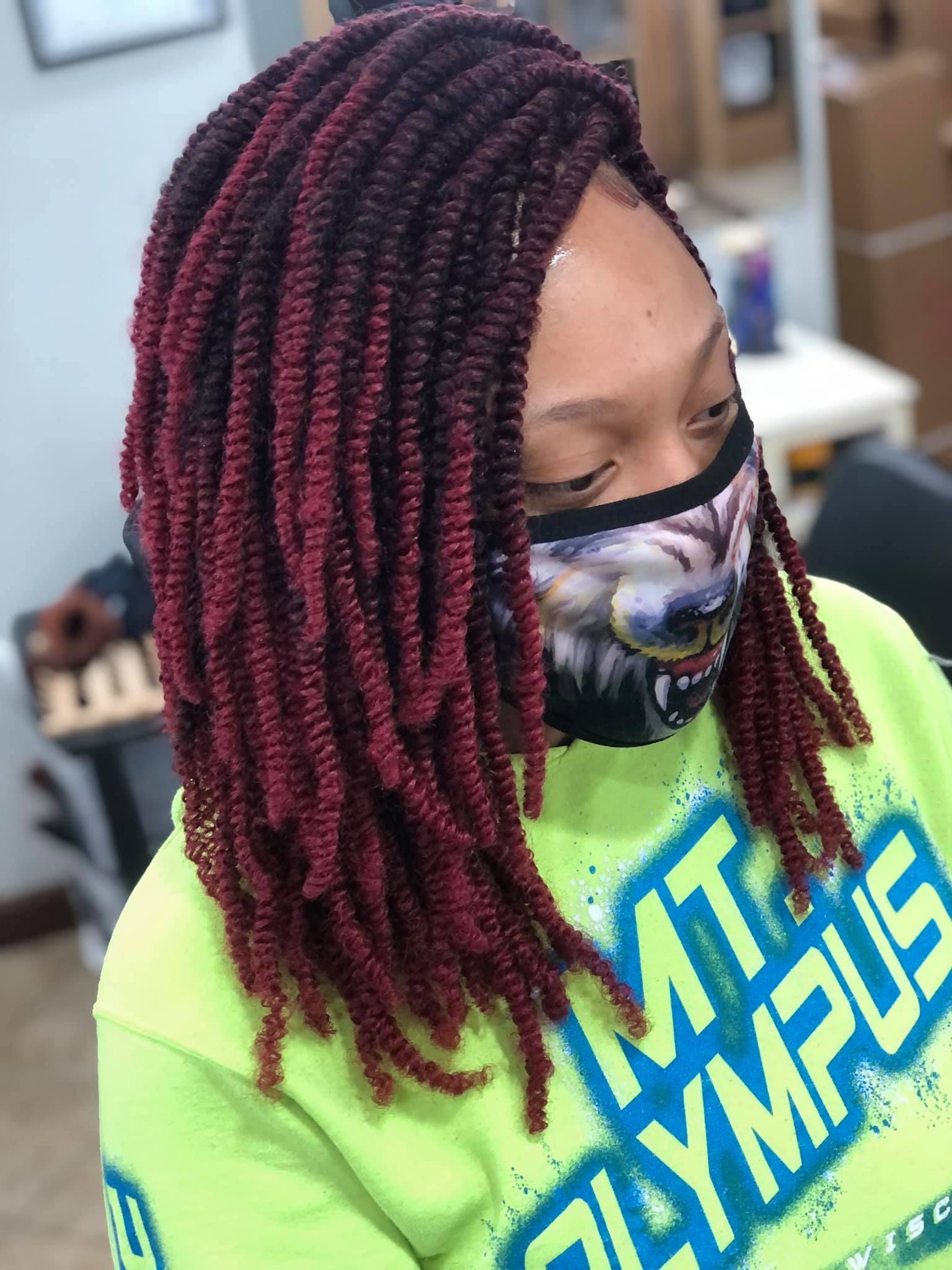 Woman with maroon-ombre twists hairstyle and wolf mask, wearing a lime green sweatshirt.