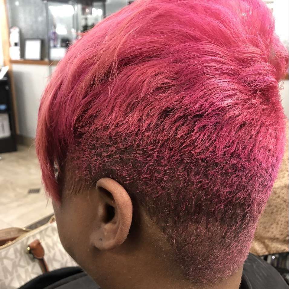Person with short, bright pink hair, shaved at the sides and back.