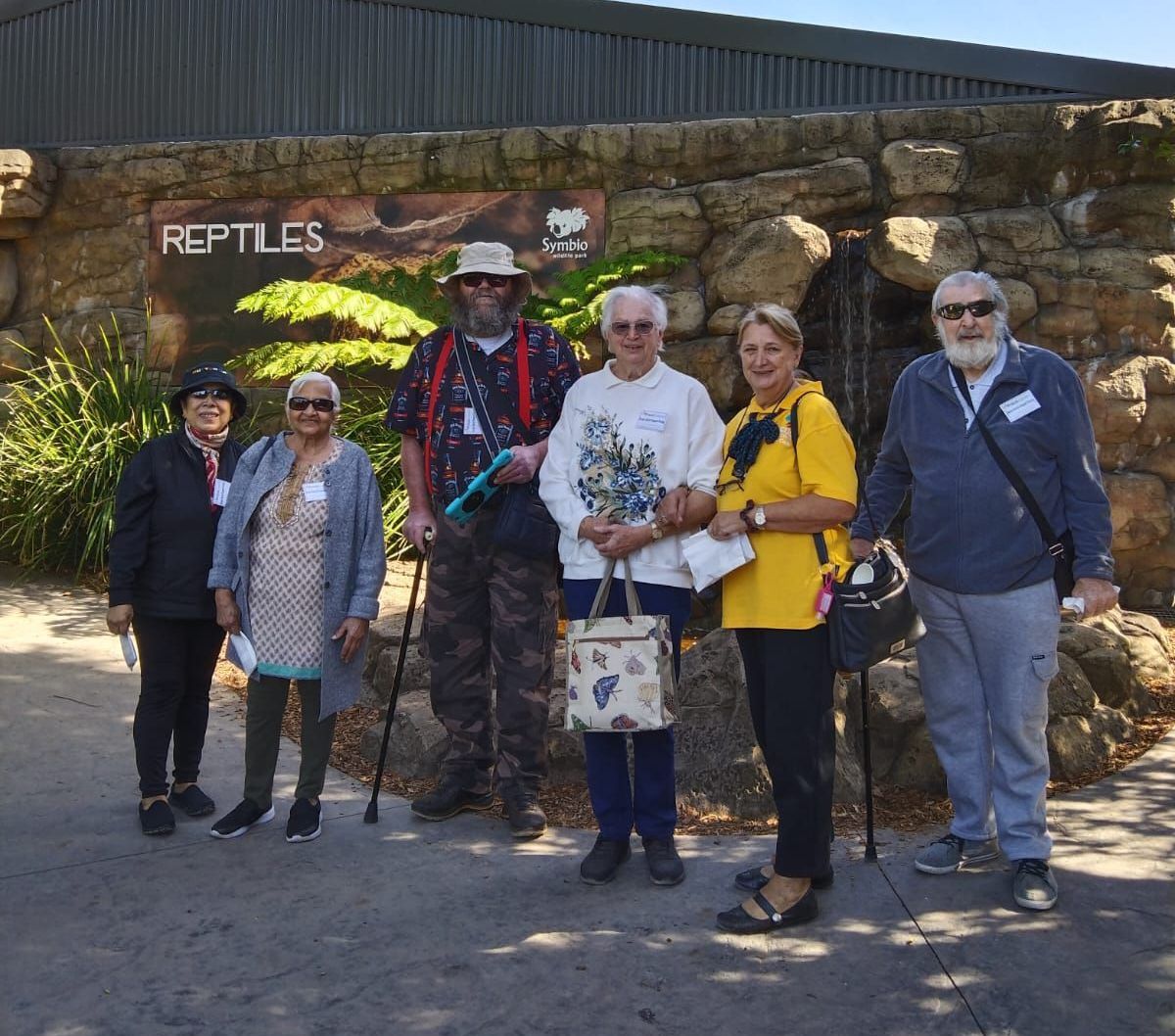 A group of people standing in front of a sign that says reptiles