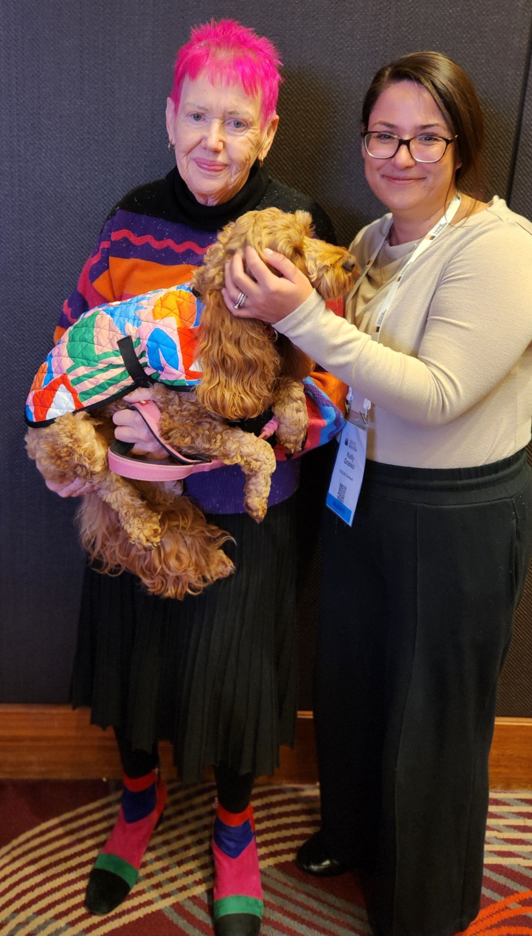 Two women are standing next to each other holding a dog.