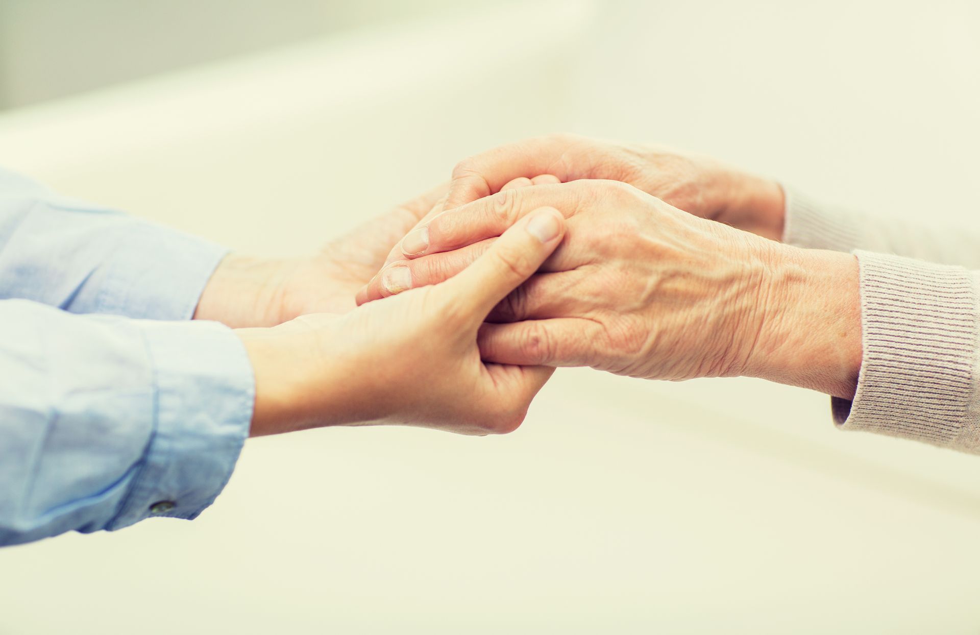 A young woman is holding an older woman's hand.