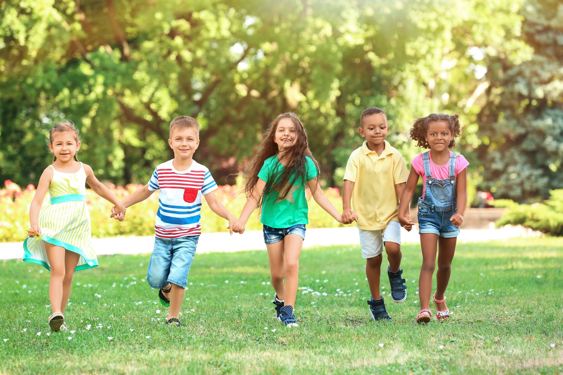 a group of children are holding hands and running in a park