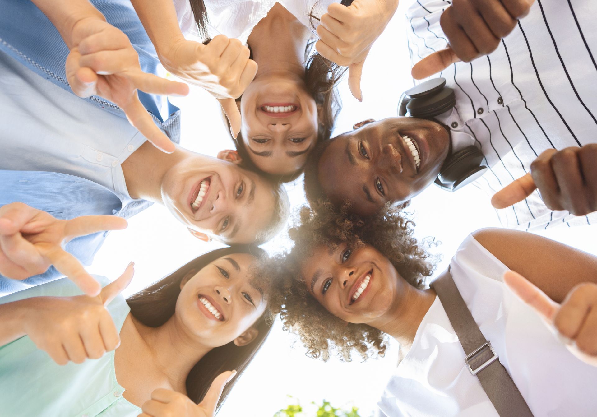 A group of young people are standing in a circle giving a thumbs up.