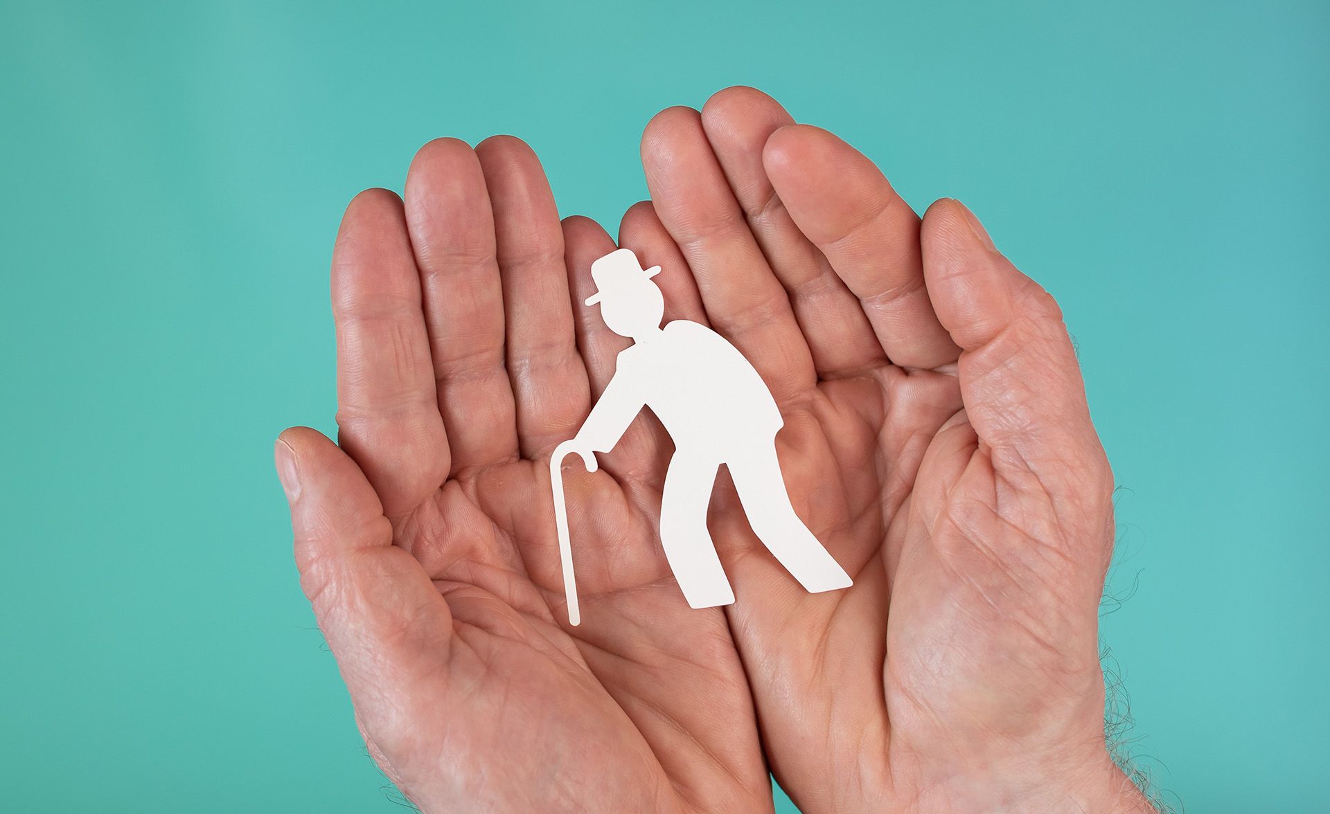 A person is holding a paper cut out of an elderly man with a cane.